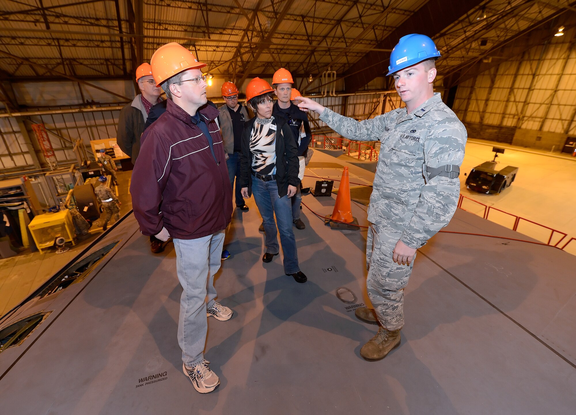 First Lt. Jay Spada, 436th Maintenance Squadron flight commander, briefs James Murray, 436th MXS honorary commander, and other visitors on the maintenance efforts underway on a C-5B Galaxy during the 2015 Dover Air Force Base Honorary Commanders tour of the 436th Maintenance Group April 15, 2015, on Dover AFB, Del. Spada briefs while standing on top of the right wing of the Air Force's largest production aircraft. (U.S. Air Force photo/Greg L. Davis)