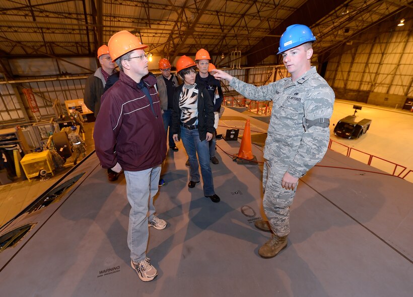 First Lt. Jay Spada, 436th Maintenance Squadron flight commander, briefs James Murray, 436th MXS honorary commander, and other visitors on the maintenance efforts underway on a C-5B Galaxy during the 2015 Dover Air Force Base Honorary Commanders tour of the 436th Maintenance Group April 15, 2015, on Dover AFB, Del. Spada briefs while standing on top of the right wing of the Air Force's largest production aircraft. (U.S. Air Force photo/Greg L. Davis)