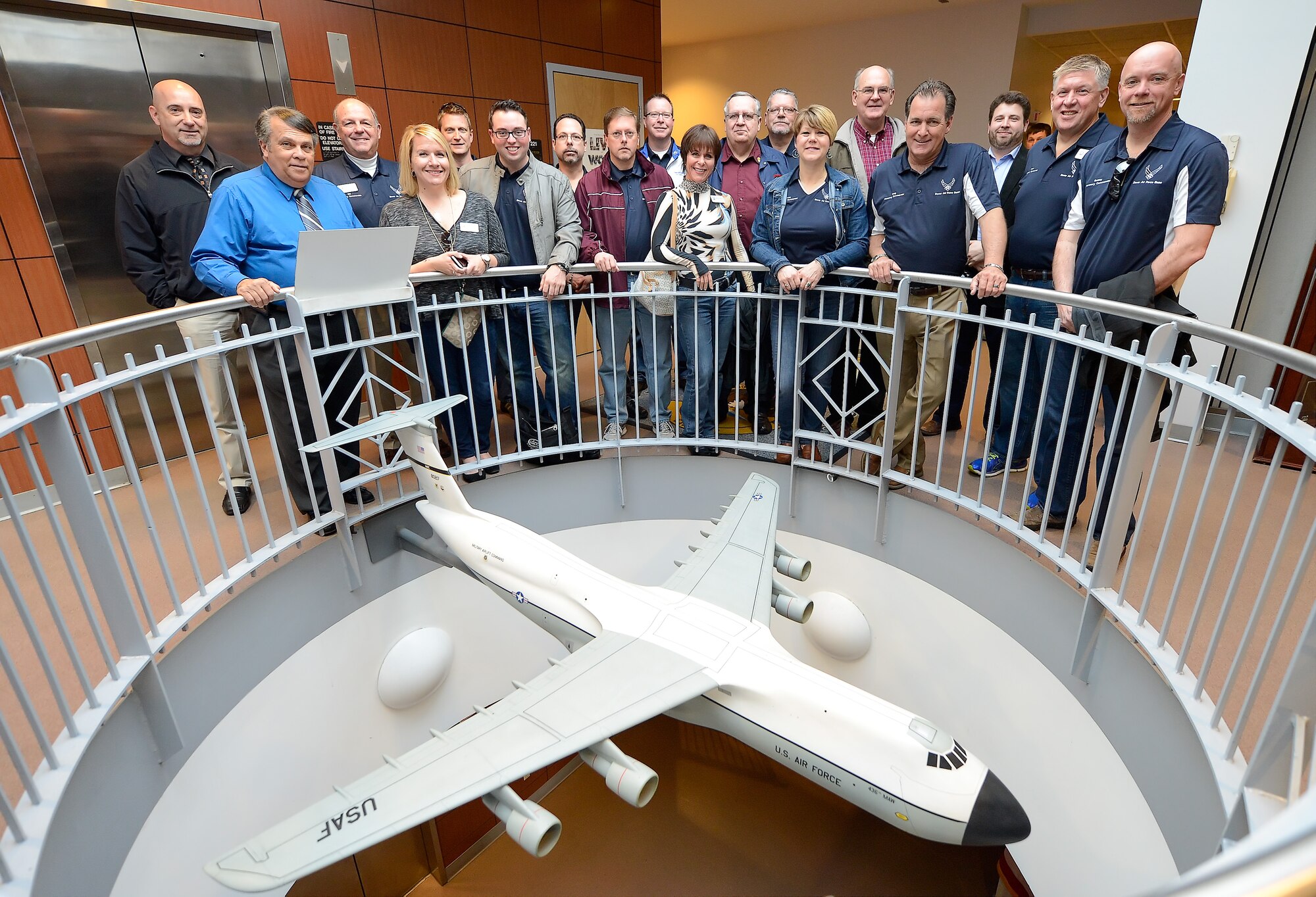 The 2015 Dover Air Force Base Honorary Commanders pose with a model of a C-5 Galaxy displayed inside the main building used by the 436th Maintenance Group April 15, 2015, on Dover AFB, Del. The group received a tour of the facility and aircraft maintained by the 436th MXG. (U.S. Air Force photo/Greg L. Davis)