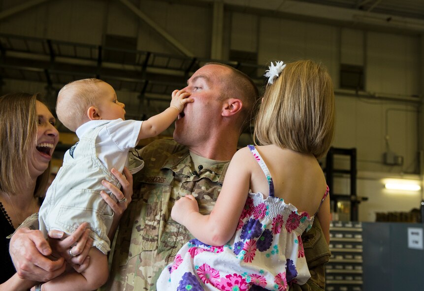 U.S. Air Force Staff Sgt. Jonathan Rhodes, 23d Logistics Readiness Squadron, reacquaints with his family during his surprise redeployment April 14, 2015, at Moody Air Force Base, Ga. Rhodes deployed 10 days after his son's birth. (U.S. Air Force photo by Airman 1st Class Ceaira Tinsley/Released)