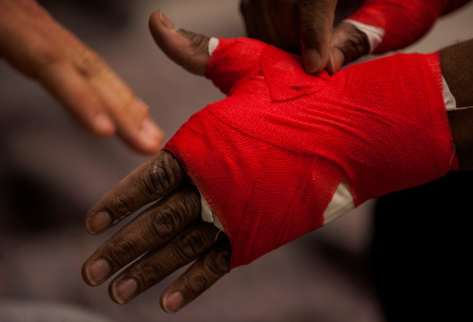 U.S. Air Force Tech. Sgt. Clinton Williams, 52nd Component Maintenance Squadron engine manager, wraps his hands before his fight during the 12th Kwon Respect Fighting Championship in Wuppertal, Germany, April 11, 2015. Williams trains in Muay Thai and Jiu Jitsu for his mixed martial arts fights. (U.S. Air Force photo by Airman 1st Class Timothy Kim/Released)