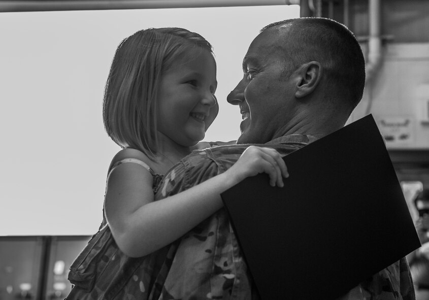 U.S. Air Force Staff Sgt. Jonathan Rhodes, 23d Logistics Readiness Squadron, and his daughter Madison, embrace during his surprise redeployment April 14, 2015, at Moody Air Force Base, Ga. Rhodes surprised his daughter by showing up to her coining ceremony. (U.S. Air Force photo by Airman 1st Class Ceaira Tinsley/Released)