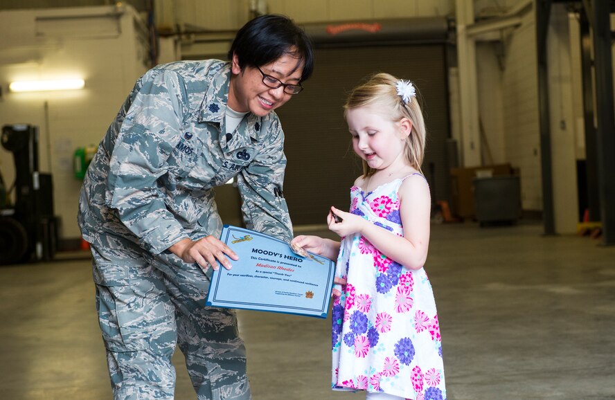 U.S. Air Force Lt. Col. Laura Ramos, 23d Logistics Readiness Squadron commander, presents Madison Rhodes, daughter of Staff Sgt. Jonathan Rhodes, 23d LRS, with two coins and a certificate during a surprise redeployment April 14, 2015, at Moody Air Force Base, Ga. The 23d LRS recently implemented a new program called Moody’s Heroes to recognize children of deployed Airmen. (U.S. Air Force photo by Airman 1st Class Ceaira Tinsley/Released)