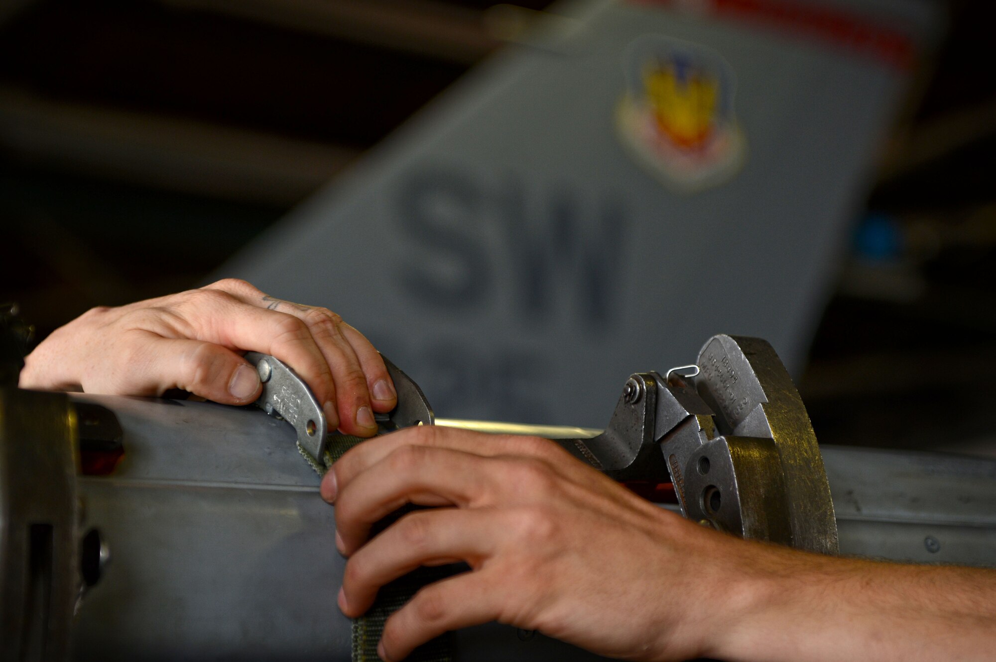 U.S. Air Force Airmen assigned to the 20th Equipment Maintenance Squadron pull a buckle to release the straps on an AIM-120 missile on an F-16CM Fighting Falcon during a load crew of the year competition at Shaw Air Force Base, S.C., April 17, 2015. During the competition teams loaded four munitions onto the aircraft testing their proficiency and combat readiness. (U.S. Air Force photo by Senior Airman Jensen Stidham/Released) 
