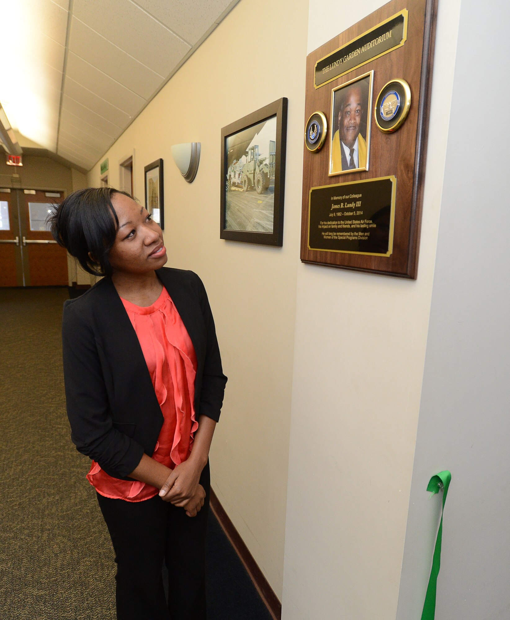 Emerald Lundy looks at her father’s plaque after the ceremony rededicating the Garden Auditorium to the Lundy-Garden Auditorium in Building 1614, April 16. James R. Lundy III, a longtime employee on base, passed away suddenly late last year. (U.S. Air Force photo by Jerry Saslav)