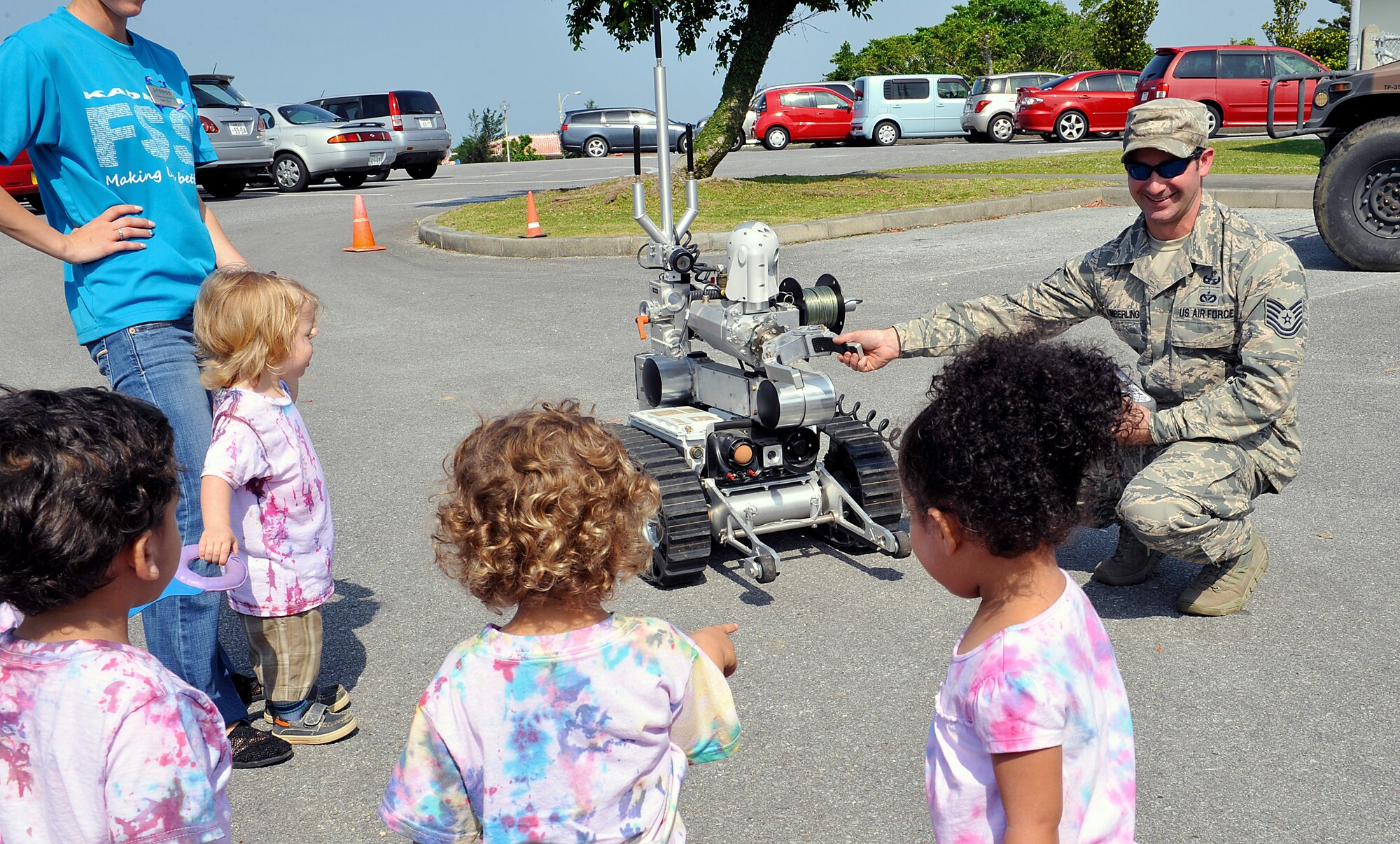 U.S. Air Force Tech. Sgt. Mathew Kimberling, 18th Civil Engineer Squadron explosive ordnance disposal technician, asks children to shake hands with an explosive ordnance disposal robot during a Military Child Appreciation Month showcase on Kadena Air Base, Japan, April 17, 2015. April is designated as Military Child Appreciation Month, underscoring the important role military children play in the armed forces community. (U.S. Air Force photo by Naoto Anazawa)