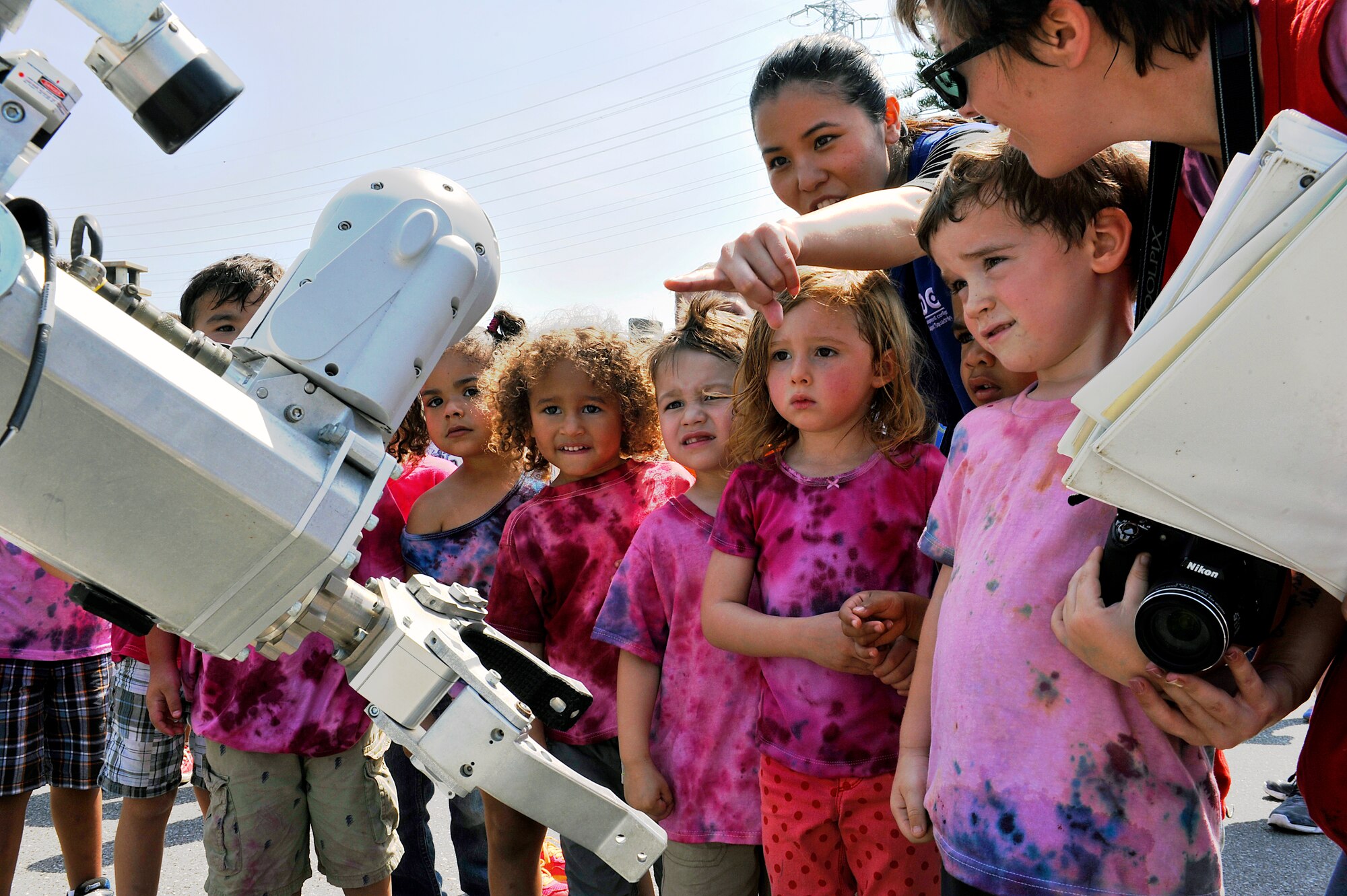 Yuki Nakahara, Niko-Niko Child and Youth Program assistant preschool caregiver, points to a lens of an explosive ordnance disposal robot during a Military Child Appreciation Month showcase on Kadena Air Base, Japan, April 17, 2015. In 1986, Defense Secretary Casper Weinberger designated April as the Month of the Military Child. Since then, military installations, organizations and communities have created special events to recognize the important role military children play in the armed forces community. (U.S. Air Force photo by Naoto Anazawa)