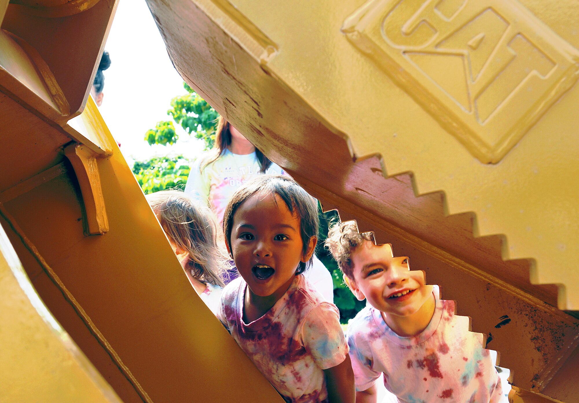 Jiraiya Duremdez, from the Niko-Niko Child Development Center, peeks through the arm of a hydraulic excavator during a Military Child Appreciation Month showcase on Kadena Air Base, Japan, April 17, 2015. The 18th Civil Engineer Squadron demonstrated their equipment at the Niko-Niko CDC in support of Military Child Appreciation Month. (U.S. Air Force photo by Naoto Anazawa)