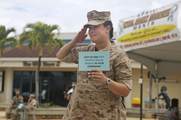 Capt. Penny MacCormack, a supply officer with 3rd Radio Battalion, freezes while rendering a salute during a freeze mob event April 14, 2015, at Mokapu Mall aboard Marine Corps Base Hawaii. When given the signal, service members froze for three minutes and held up signs containing sexual assault awareness and prevention messages, providing information ranging from statistics to some contributing factors of sexual assault. The goal of the freeze mob event was to grab the attention of bystanders and get them to notice the signs, raising awareness for Sexual Assault Awareness Month, observed in the month of April. (U.S. Marine Corps photo by Lance Cpl. Harley Thomas/Released)
