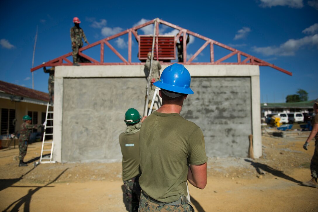 U.S. Marine Lance Cpl. Wyatt Floyd, center, assigned to the 9th Engineer Support Battalion, helps place a roof truss along with U.S. Navy Seabees, assigned to Naval Mobile Construction Battalion 5, and Armed Forces of the Philippines Army engineers from the 552nd Engineer Construction Battalion, at Don Joaquin Artuz Memorial Elementary School in Tapaz, Philippines, during Balikatan 2015, April
16. The engineers are part of the Joint Civil-Military Operations Task Force on the island of Panay constructing two classrooms at the school. Balikatan, which means “shoulder to shoulder” in Filipino, is an annual bilateral training exercise aimed at improving the ability of Philippine and U.S. military forces to work together during planning, contingency, humanitarian assistance and disaster relief operations. (U.S. Navy photo by Chief Mass Communication Specialist Lowell Whitman/Released)