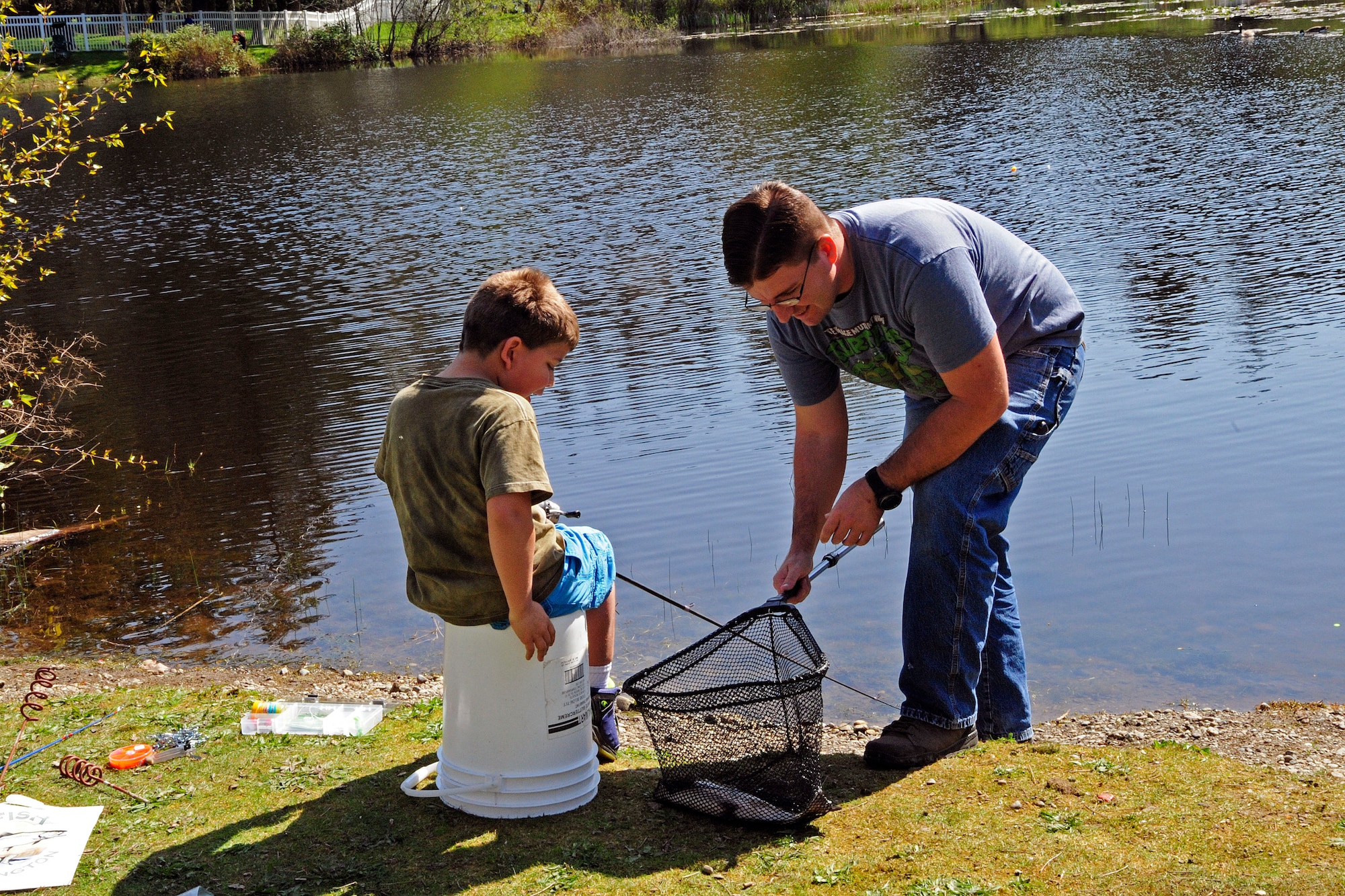 Spc. Dustin Jones (right), 525th Military Police Battalion supply sergeant for camp operations, and his son inspect their catch during the Top III Annual Children's Fishing Derby, April  18, 2015, at Carter Lake on Joint Base Lewis-McChord, Wash. The lake was stocked with an estimated 1,250 rainbow trout of varying size for the event, giving children plenty of chances to catch their own fish. (U.S. Air Force photo/Senior Airman Rebecca Blossom)
