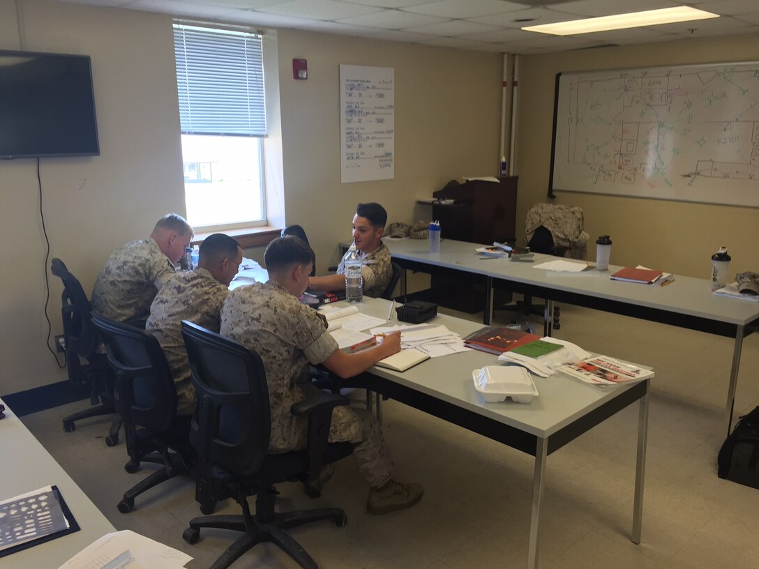 Marines from AE 2-15 conduct practical application on interior wiring blueprints.