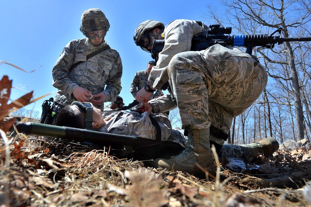 Airmen provide medical aid to a simulated wounded airman at a casualty collection point during a "force on force" training exercise on Camp Smith, New York, April 12, 2015. 

