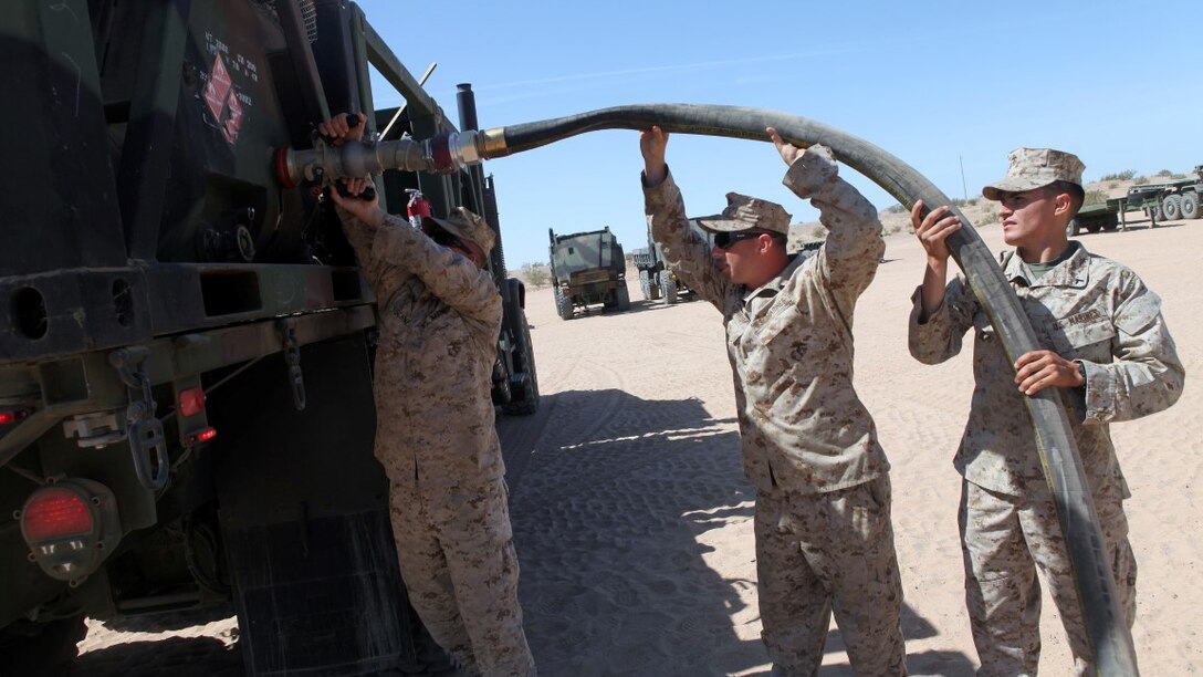 Private First Class Brenen Tischner, left, a motor transportation operator, with 1st Transport Support Battalion, Combat Logistics Regiment 1, 1st Marine Logistics Group, attaches a fuel hose to an AMK-23 Medium Tactical Vehicle Replacement with the help of two other Marines during routine refueling maintenance on the outskirts of Marine Corps Air Station Yuma, Arizona, April 10, 2015. Tischner inspects vehicles like this each day to ensure optimum reliability for logistic units supporting the bi-annual, seven-week long Weapons Tactics and Instructor course at MCAS Yuma and the surrounding area. WTI, hosted by Marine Aviation Weapons and Tactics Squadron 1, provides advanced tactical training to certify Marine pilots as weapons and tactics instructors, preparing them to serve in key training officer billets in the fleet Marine force. (Marine Corps photo by Sgt. Cody Haas/Released)