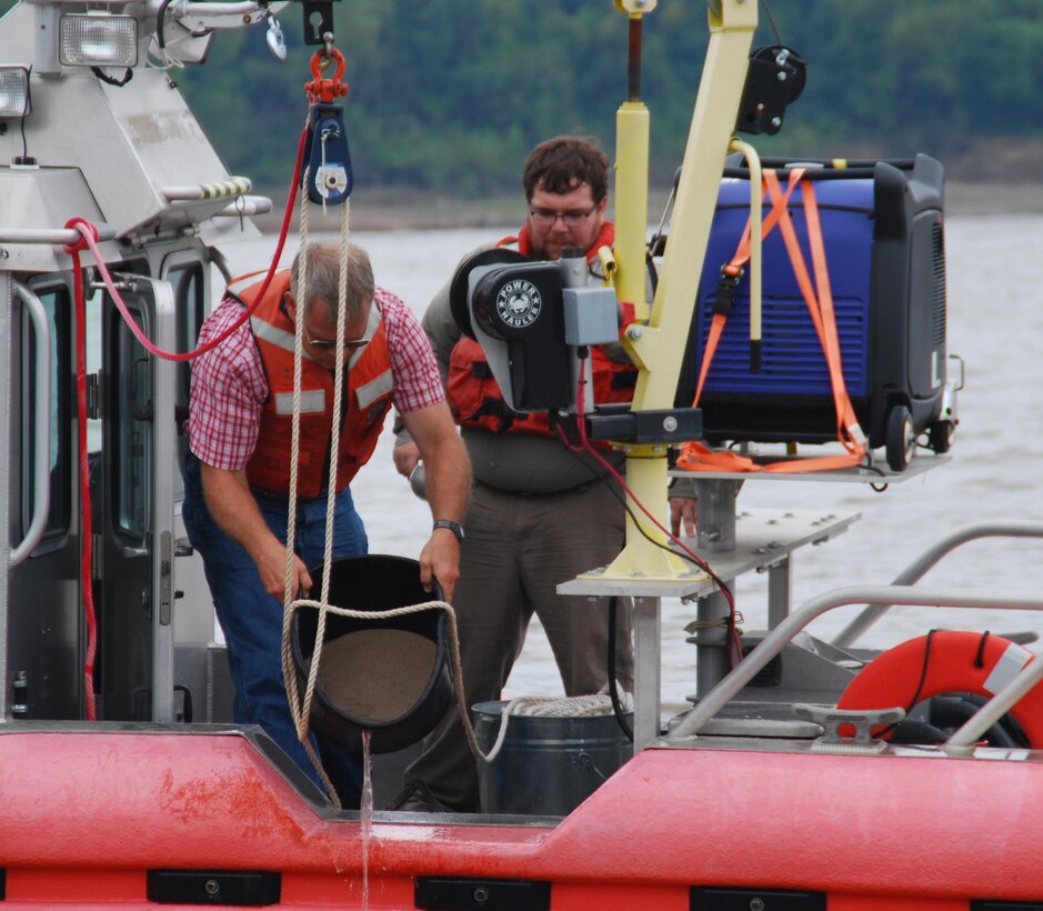 Thad Pratt, ERDC, and Richie McComas of the Corps' Vicksburg District, pour off excess water from a river sediment sample prior to bagging and logging. 