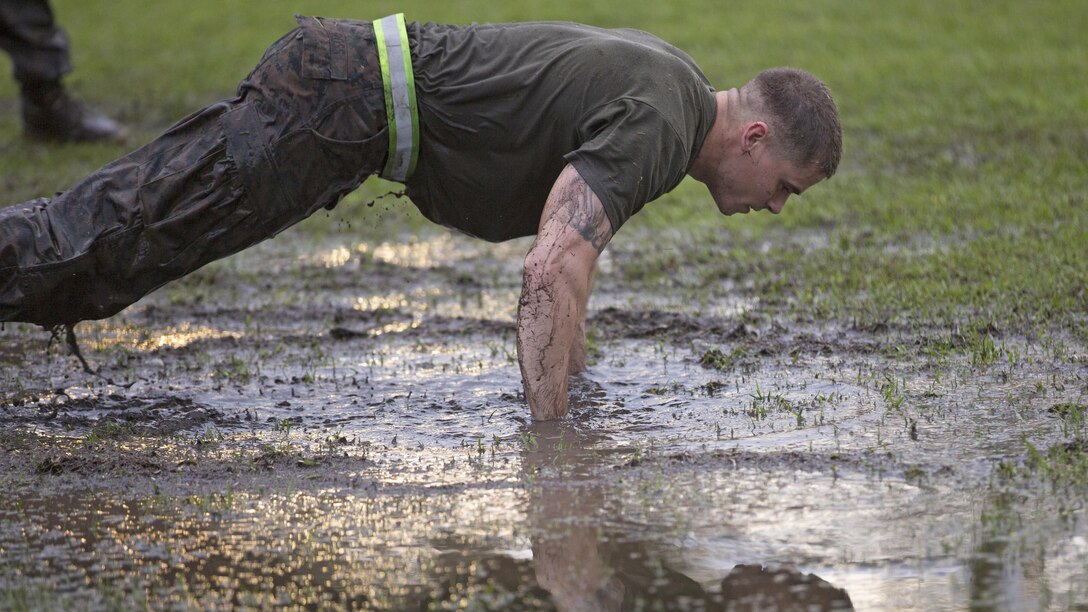 Lance Cpl. Matthew Ross, a machine gunner and student at the Advanced Machine Gunner Course, Advanced Infantry Training Battalion-East, performs “burpees” in the mud as part of physical training during AMGC, aboard Camp Geiger, N.C., April 20, 2015. The goal of physical training throughout this course is to push the students past their limits to build a strong mind and body.