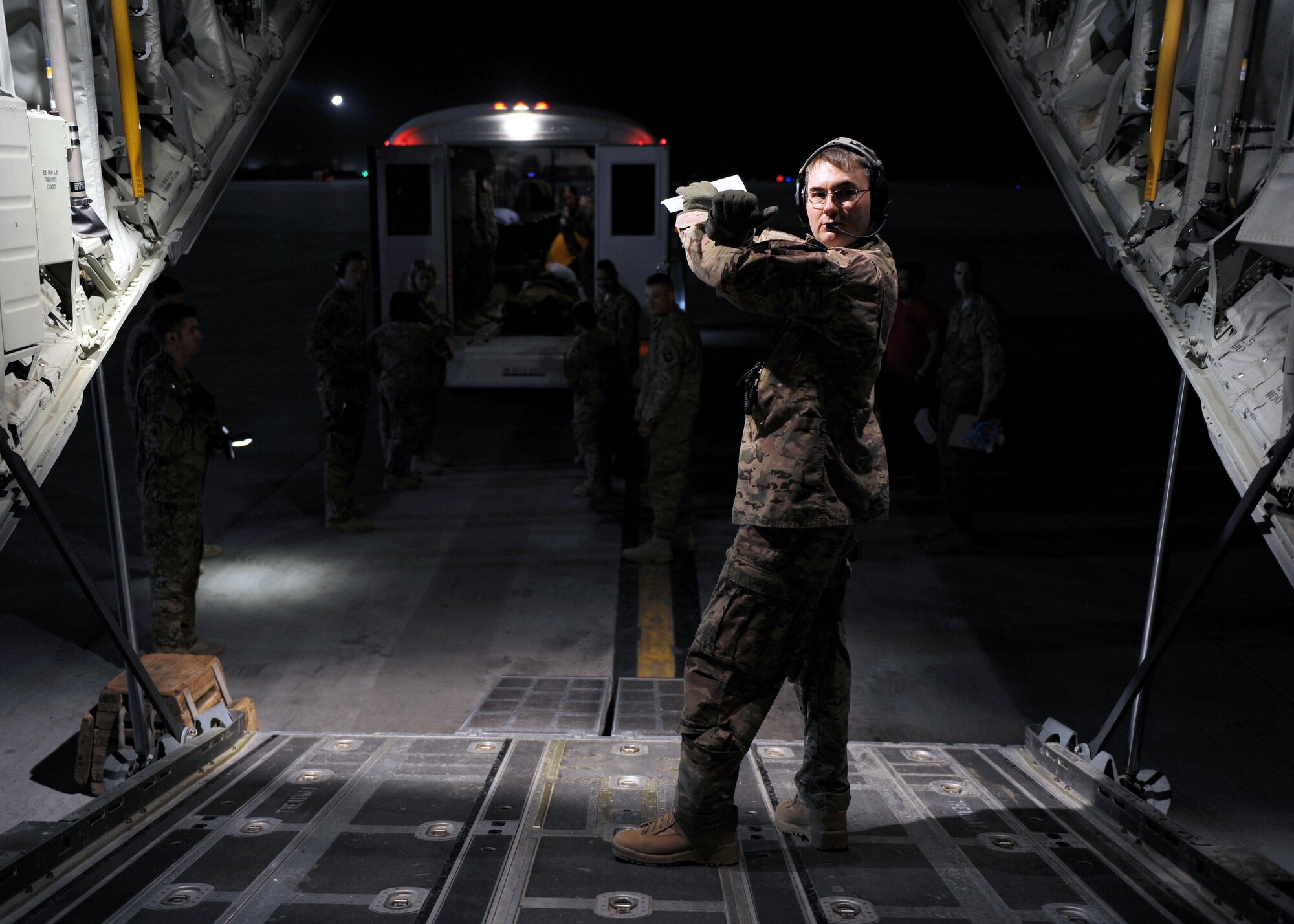 U.S. Air Force Maj. Fred Pounds, 455th Expeditionary Aeromedical Evacuation Squadron flight nurse, communicates with a litter team using hand signals during an AE mission April 19, 2015 at Kandahar Airfield, Afghanistan. 455 EAES Airmen are charged with the responsibility of evacuating the sick and wounded from Central Command to higher echelons of medical care. (U.S. Air Force photo by Staff Sgt. Whitney Amstutz/released)