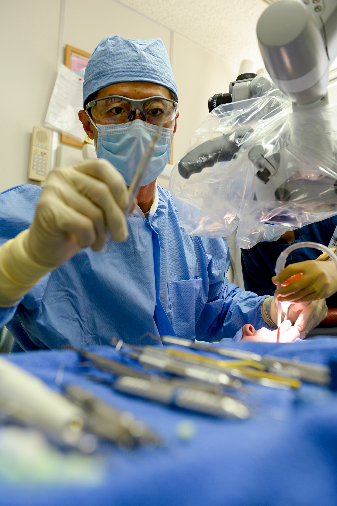 During a root-end surgery, 374th Dental Squadron Endodontics chief, Maj. Jongsun Kim, selects from an array of dental tools April 16, 2015 Yokota Air Base, Japan. The 374 DS supports Yokota Air Base by performing more than 400 dental surgeries per year. (U.S. Air Force photo by Airman 1st Class Elizabeth Baker/Released)