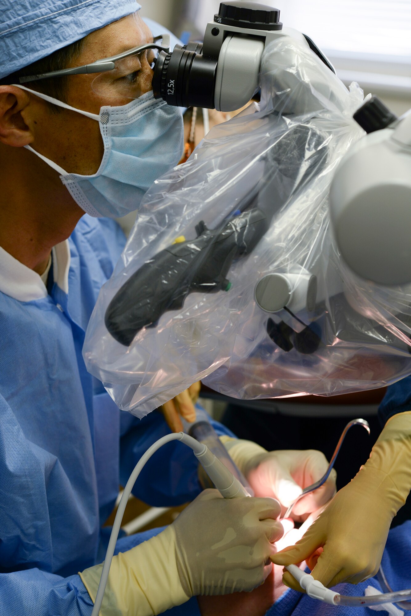 Observing his patient through a magnification device, 374th Dental Squadron Endodontics chief, Maj. Jongsun Kim, performs a root-end surgery April 16, 2015 Yokota Air Base, Japan. Endondontics is the study and treatment of the living tissue inside the tooth. (U.S. Air Force photo by Airman 1st Class Elizabeth Baker/Released) 