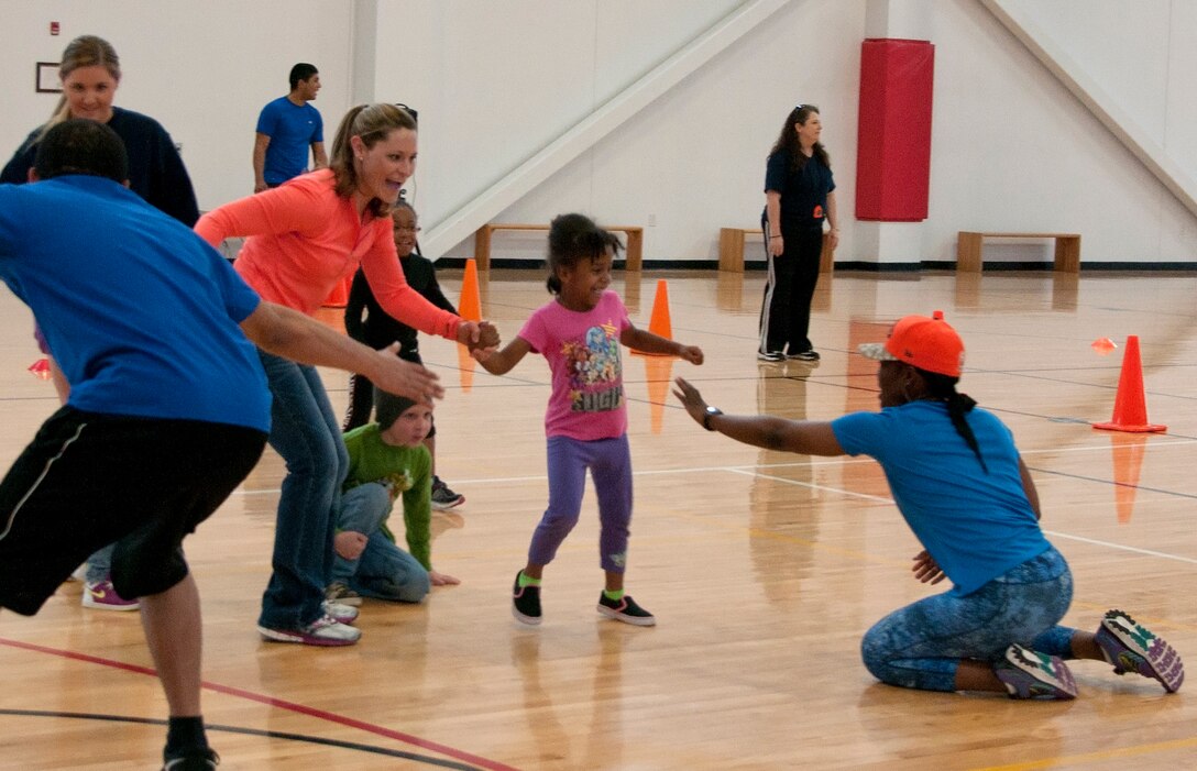 Megan Thompson and Carissa White, 6, try to avoid Tech. Sgt. Curnita Brigsby, 90th Security Forces Squadron, while playing a game of octopus April 18, 2015, during the 90th Force Support Squadron Family Fun Competition event in the Freedom Hall Fitness Center, F.E. Warren Air Force Base, Wyo. Octopus is played by trying to avoid being tagged by the octopus, three people whose arms are linked together. (U.S. Air Force photo by Airman 1st Class Brandon Valle)