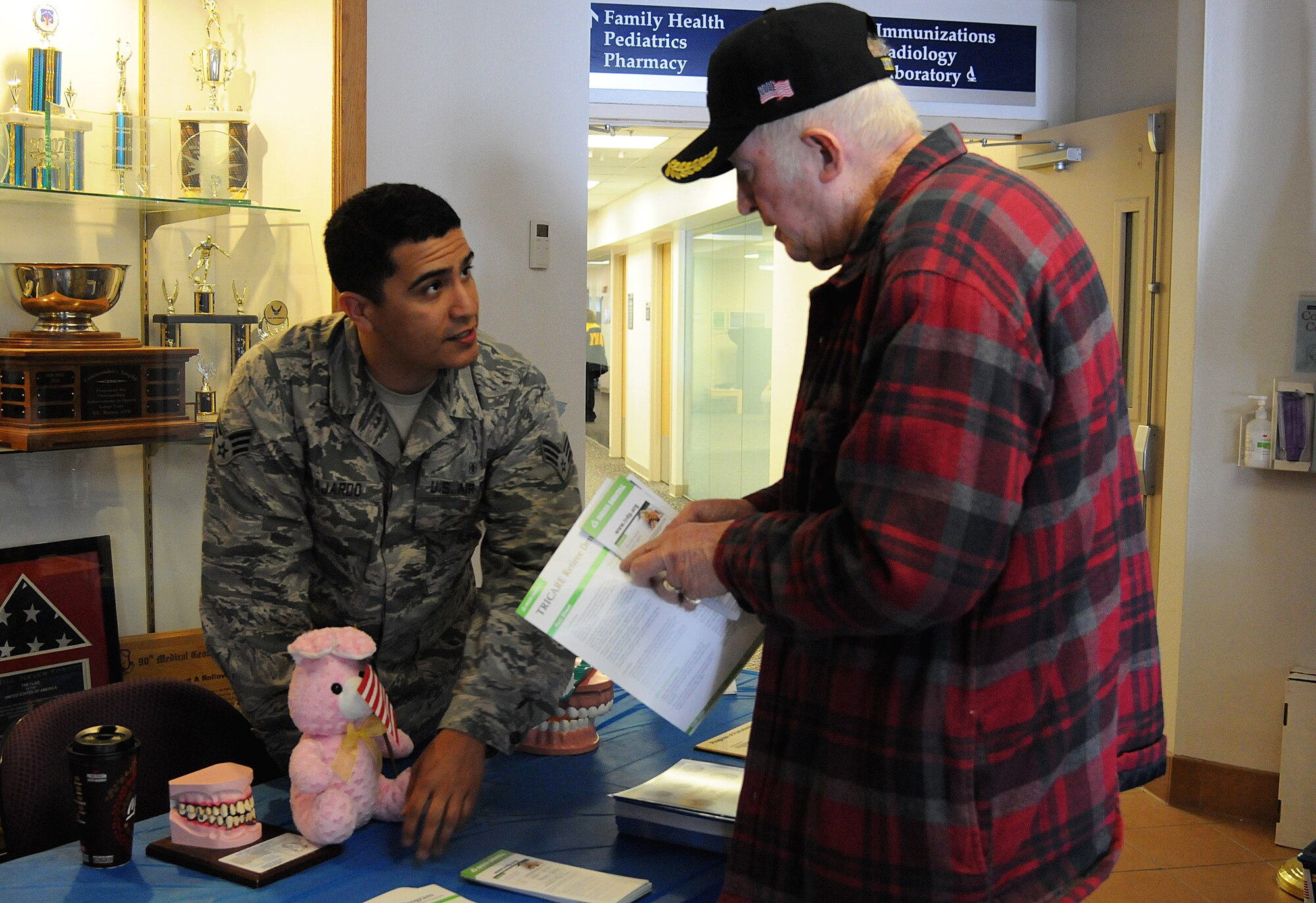 Senior Airman Miguel Guajardo, 90th Medical Operations Squadron dental assistant, discusses dental hygiene and nutrition with a retiree April 18, 2015, during a Retiree Appreciation Day in the Medical Treatment Facility on F.E. Warren Air Force Base, Wyo. Airmen manned informational booths to explain services the base has to offer retirees. (U.S. Air Force photo by Airman 1st Class Malcolm Mayfield)