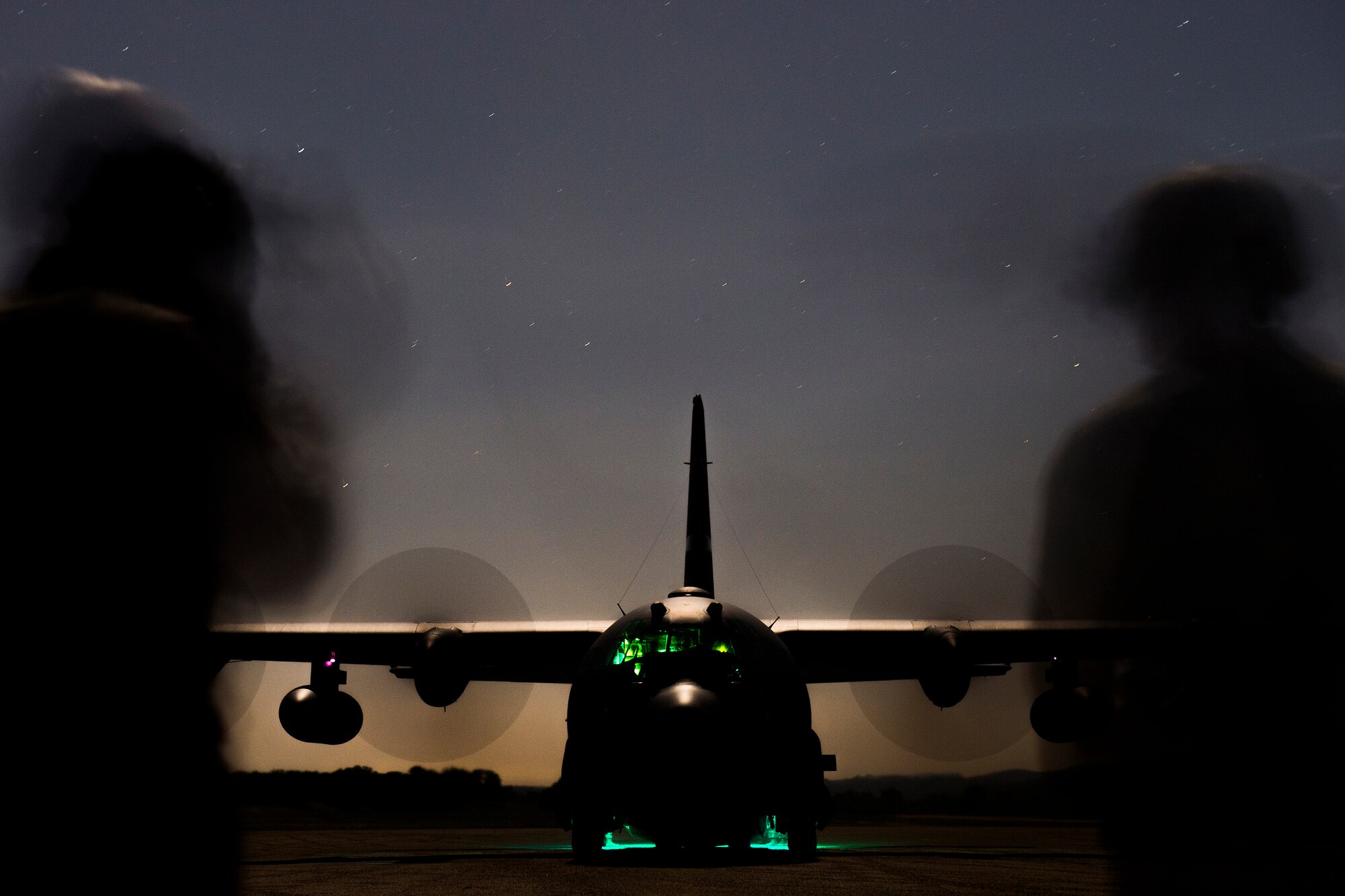 Senior Airman Michael Wilkinson an aircraft maintenance technician with the 570th Global Mobility Squadron, instructs Airman First Class Jacob Brooks, on low light engine running on load procedures for a C-130 Hercules Aircraft at Fort Hunter Liggett, Calif. during Exercise Golden Hydra on March 31, 2015. (Photo by U.S. Air Force Photojournalist Tech. Sgt. Matthew Hannen)   