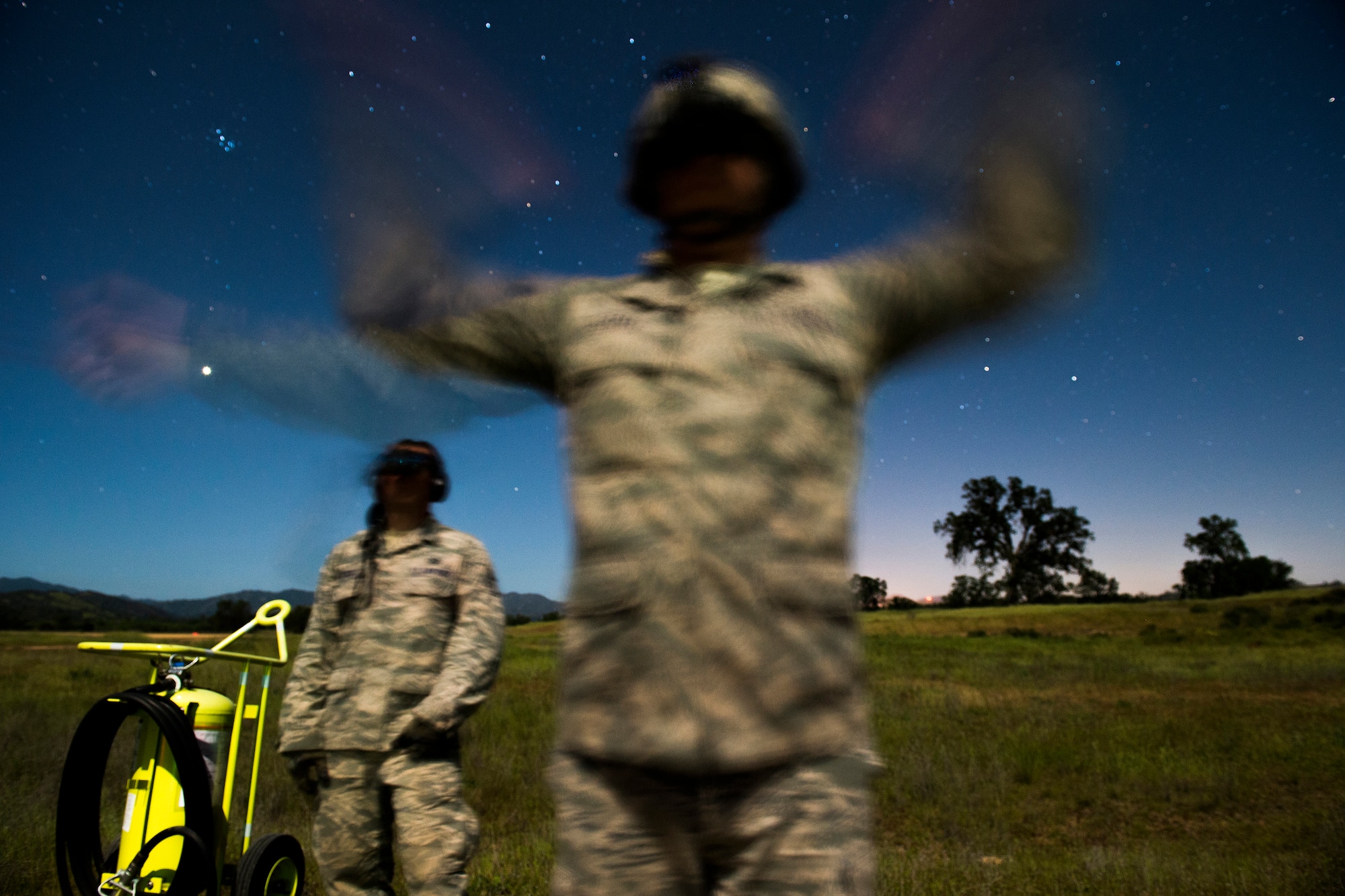 Senior Airman Michael Wilkinson an aircraft maintenance technician with the 570th Global Mobility Squadron, instructs Airman First Class Jacob Brooks, on low light engine running on load procedures for a C-130 Hercules Aircraft at Fort Hunter Liggett, Calif. during Exercise Golden Hydra on March 31, 2015. (Photo by U.S. Air Force Photojournalist Tech. Sgt. Matthew Hannen)   