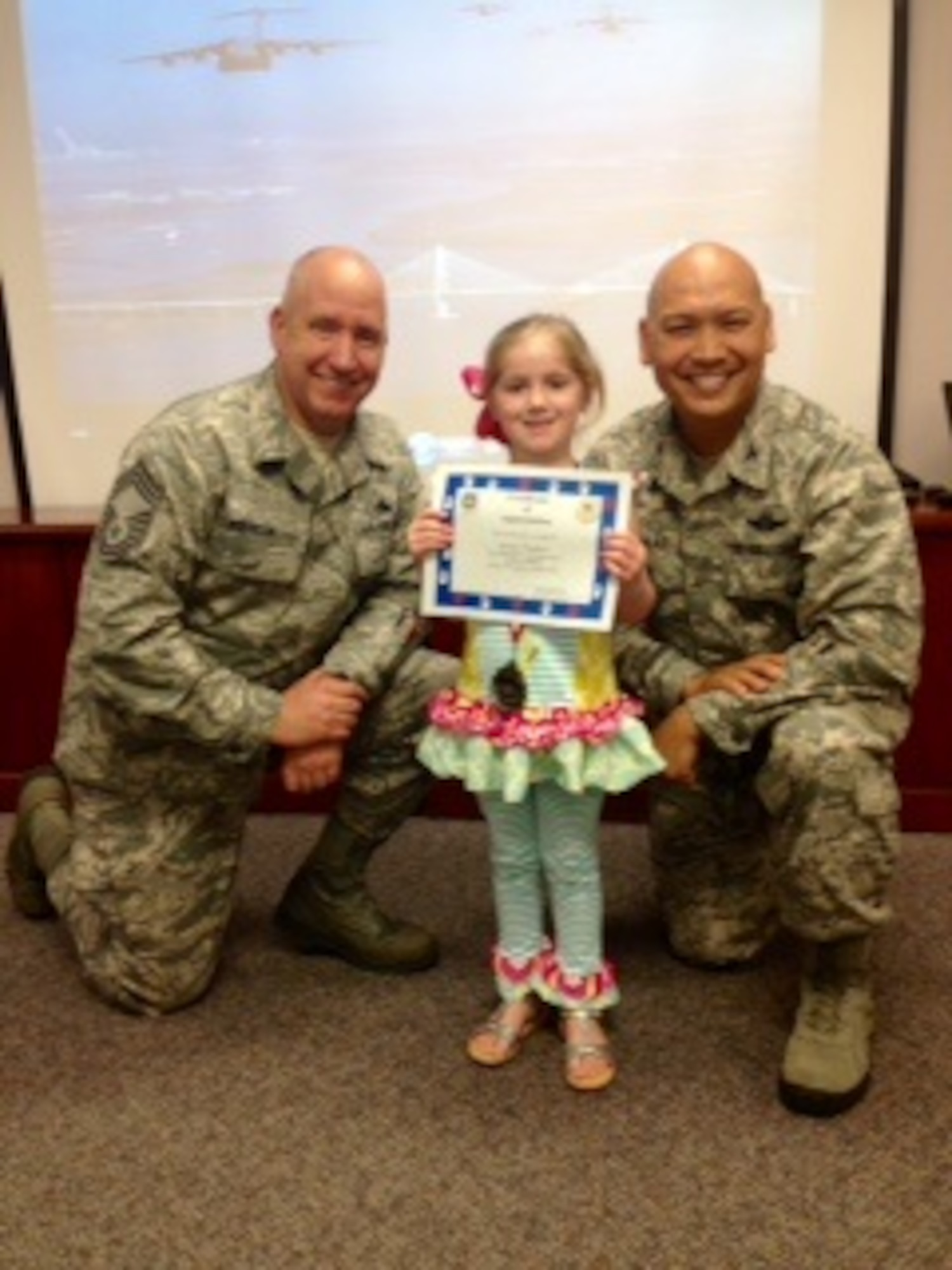 Chief Master Sgt. Christopher Robinson, 437th Maintenance Group superintendent (left) and Col. Jimmy Canlas, 437th Airlift Wing vice commander present Kinsley Wardlow with a medal and certificate during the Little Heroes ceremony April 16, 2015 at the Airman and Family Readiness Center at Joint Base Charleston, S.C. Held twice a year, once in April and again in October, the ceremony is an event for children of recent or current
deployed or remote parents. This  event is a way for senior leaders to thank the base's littlest members for all of their hard work and sacrifice during the deployment or remote tour. Captain Timothy Sparks, JB Charleston deputy commander and Chief Master Sgt. Jan Menard, 628th Medical Group superintendent Sparks and Chief Menard, handed out the medals and certification for the 628th Air Base Wing. Kinsley is the daughter of April and Staff Sgt. James Wardlow, 437th Aircraft Maintenance Squadron. (Courtesy photo)