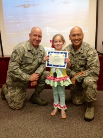 Chief Master Sgt. Christopher Robinson, 437th Maintenance Group superintendent (left) and Col. Jimmy Canlas, 437th Airlift Wing vice commander present Kinsley Wardlow with a medal and certificate during the Little Heroes ceremony April 16, 2015 at the Airman and Family Readiness Center at Joint Base Charleston, S.C. Held twice a year, once in April and again in October, the ceremony is an event for children of recent or current
deployed or remote parents. This  event is a way for senior leaders to thank the base's littlest members for all of their hard work and sacrifice during the deployment or remote tour. Captain Timothy Sparks, JB Charleston deputy commander and Chief Master Sgt. Jan Menard, 628th Medical Group superintendent Sparks and Chief Menard, handed out the medals and certification for the 628th Air Base Wing. Kinsley is the daughter of April and Staff Sgt. James Wardlow, 437th Aircraft Maintenance Squadron. (Courtesy photo)