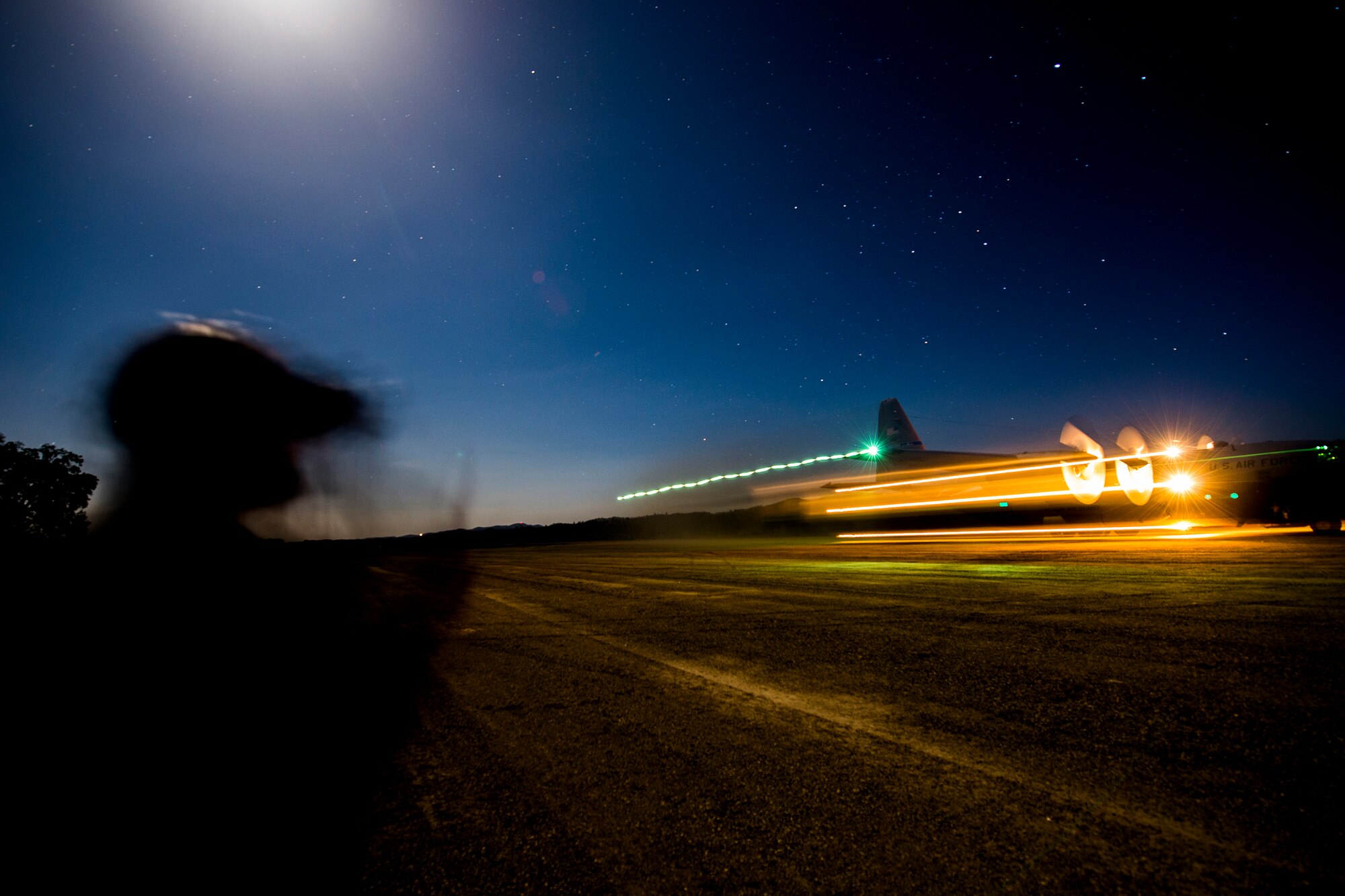 Senior Airman Michael Wilkinson an aircraft maintenance technician with the 570th Global Mobility Squadron, instructs Airman First Class Jacob Brooks, on low light engine running on load procedures for a C-130 Hercules Aircraft at Fort Hunter Liggett, Calif. during Exercise Golden Hydra on March 31, 2015. (Photo by U.S. Air Force Photojournalist Tech. Sgt. Matthew Hannen)   