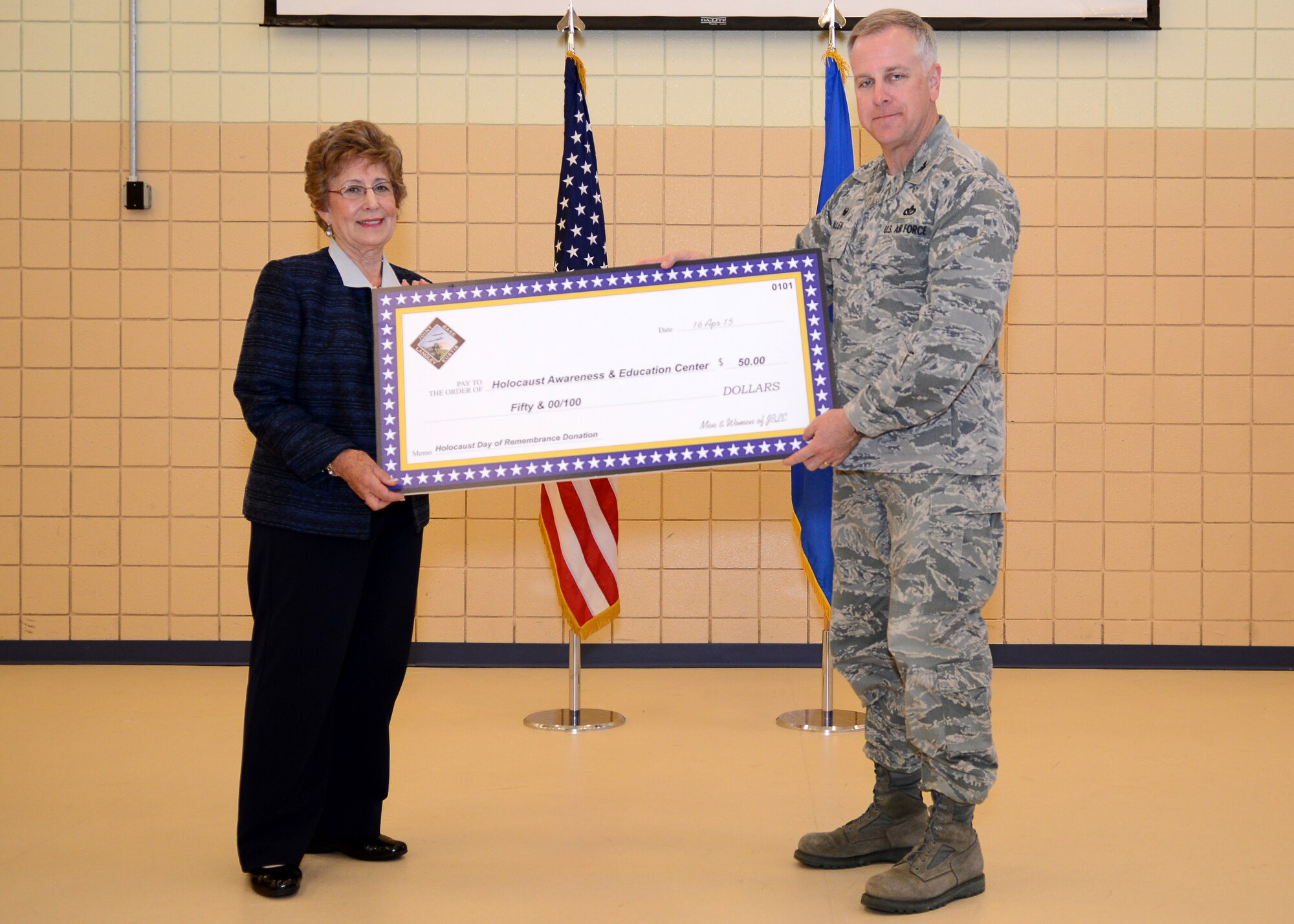 U.S. Air Force Col. John Allen, 633rd Air Base Wing commander, presents Ruth Hartz, Holocaust survivor, a donation of fifty dollars for the Holocaust Remembrance and Education Center at Langley Air Force Base, Va., April 16, 2015. This year marks the 70th anniversary since the defeated Germans capitulated to allied forces. (U.S. Air Force photo by Airman 1st Class Devin S. Michaels/Released)