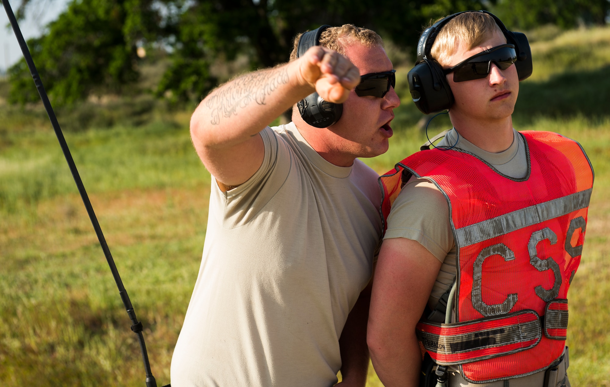 Senior Airman Michael Wilkinson, an aircraft maintenance technician with the 570th Global Mobility Squadron, instructs Airman First Class Jacob Brooks on proper procedures for marshalling a C-130 Hercules aircraft at Fort Hunter Liggett, Calif. during Exercise Golden Hydra on March 31, 2015. (Photo by U.S. Air Force Photojournalist Tech. Sgt. Matthew Hannen)  