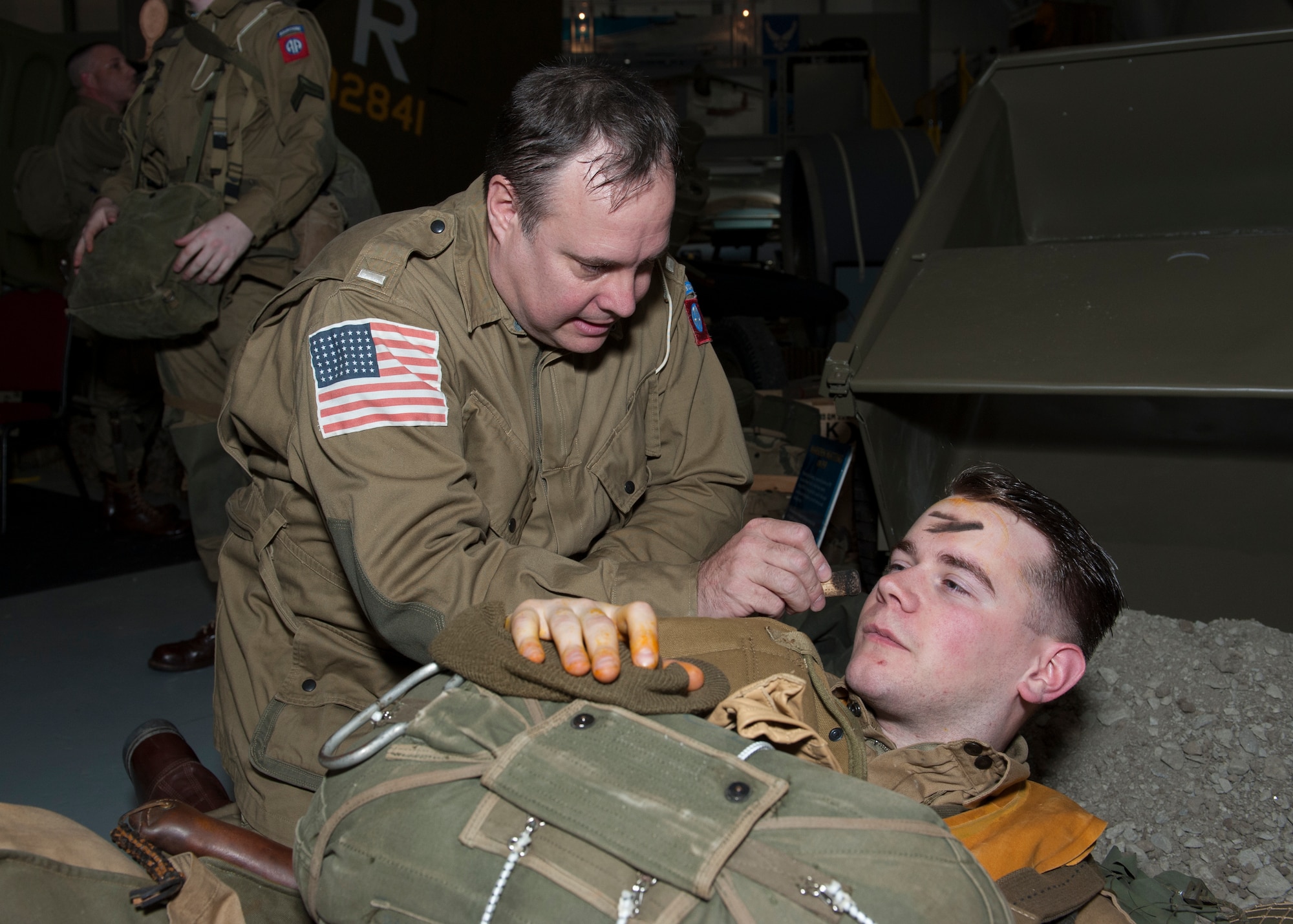 Greg Boyer applies combat face paint to the face of Daniel Dillier April 18, 2015, at the Air Mobility Command Museum near Dover Air Force Base, Del. Boyer and Dillier are members of a re-enacting group that depict World War II-era paratroopers from the 82nd Airborne Division. (U.S. Air Force photo/Airman 1st Class Zachary Cacicia)
