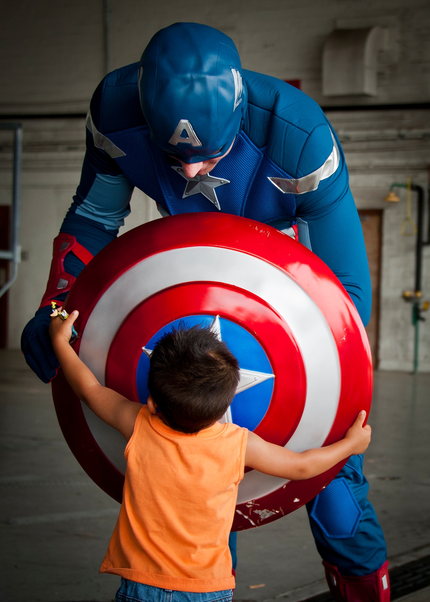 A young deployer holds tight to Captain America’s shield at Operation Hero April 18 at Eglin Air Force Base, Fla. Staff Sgt. Kurtis Harrison, of the 96th Communications Squadron, had the honor of portraying Captain America as the Air Force Materiel Command’s non-commissioned officer of the year. More than 275 kids participated in this year’s event which is a mock deployment experience created to give military children a glimpse of what their loved ones go through when they leave home. The kids went through a deployment line to get their dog tags and “immunizations” before they were briefed by the commander and shipped off to a deployed location. There, they participated in various activities and demonstrations put on by local base agencies. (U.S. Air Force photo/Sara Vidoni)
