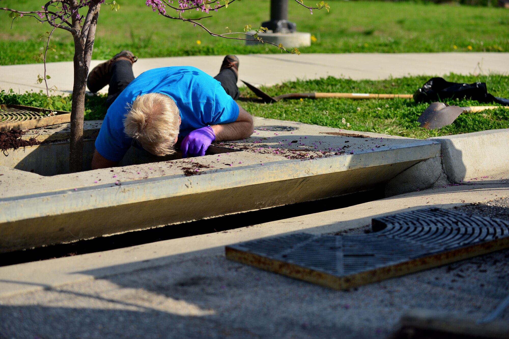 Ron Holcomb, 733rd Civil Engineer Division environmental element environment protection specialist, removes debris from a storm drain at Fort Eustis, Va., April 21, 2015. Holcomb removed the debris to clean the system and prepare to add a new water filtering mechanism to the drain.  (U.S. Air Force photo by Staff Sgt. Natasha Stannard/Released)
