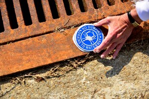 “No Dumping” medallions are placed onto storm drains at Fort Eustis, Va., April 21, 2015. The medallions indicate drains that flow directly into local Virginia waterways. Post members cleaned debris from the drains and marked them with medallions for Earth Week. (U.S. Air Force photo by Staff Sgt. Natasha Stannard/Released) 