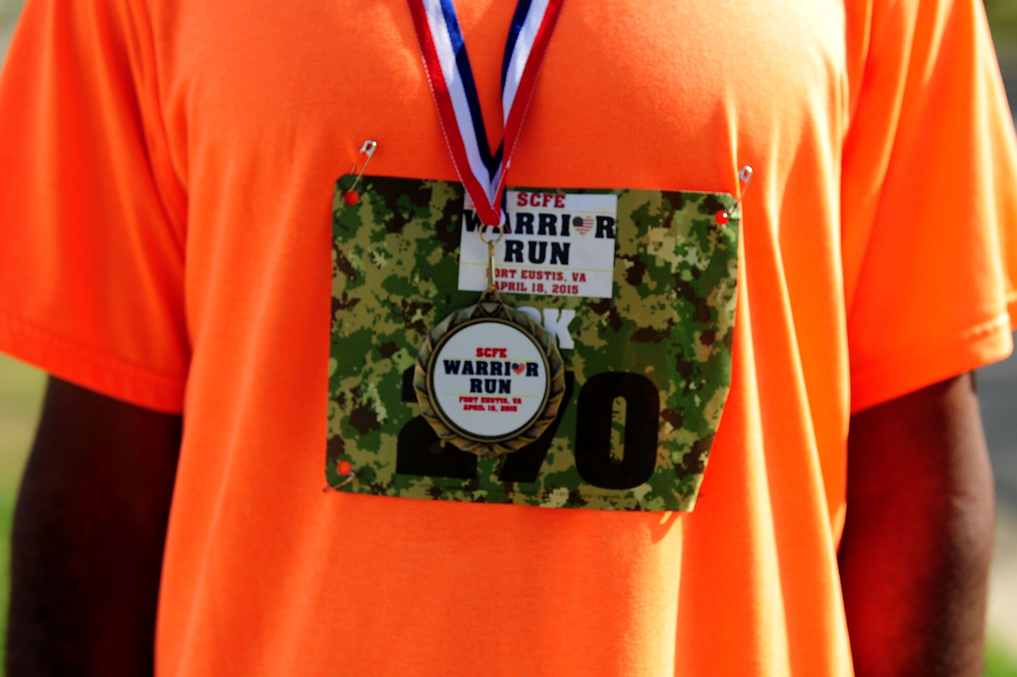 U.S. Army 1st Sgt. Paul Ellis, race participant from the 359th Inland Cargo Transfer Company, 10th Transportation Battalion, 7th Transportation Brigade (Expeditionary), dawns his medal and race bib at the Warrior Run at Fort Eustis, Va., April 18, 2015. This is the second time the Spouses' Club of Fort Eustis has put on the event, which, supports Wounded Warriors and their families. (U.S. Air Force photo by Staff Sgt. Natasha Stannard/Released)