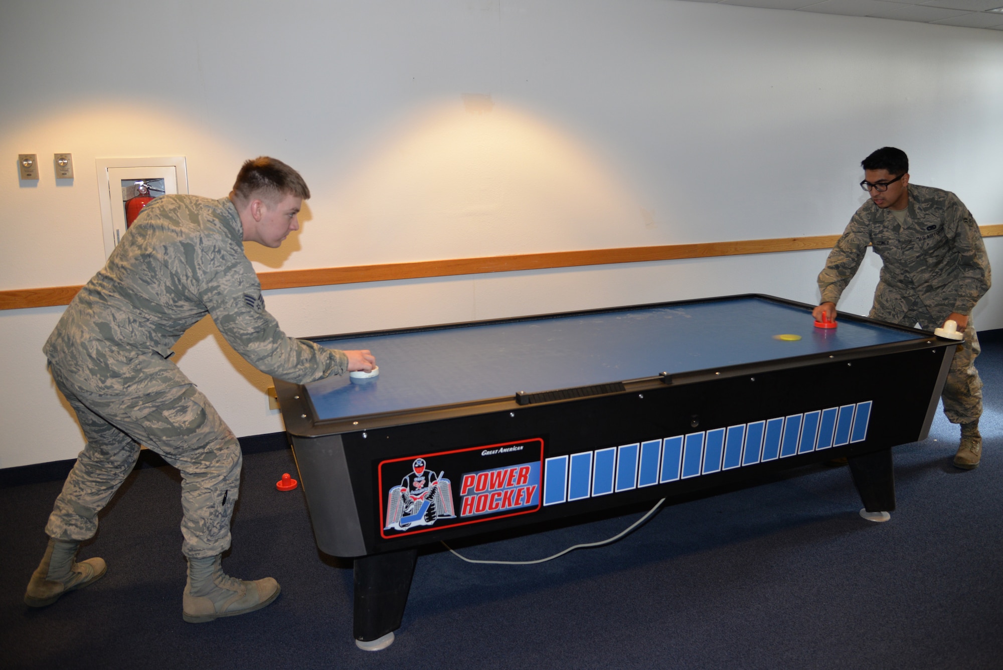 Senior Airman Kenneth Blount, 354th Force Support Squadron and Airman 1st Class Jesus Gomez, 354th Aircraft Maintenance Squadron, try out a new air hockey table recently added to the common room of their dormitory. Dormitory residents are able to enjoy approximately $30,000 in quality of life upgrades to the common rooms of dormitory buildings. (U.S. Air Force photo by Staff Sgt. Kirsten Wicker/Released)