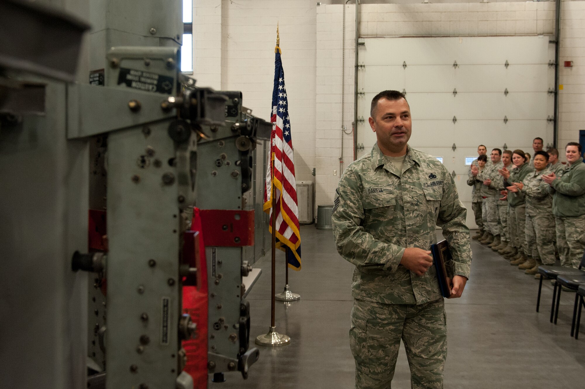 Master Sgt. Marshall J. Daniell, an armament systems specialist with the 124th Aircraft Maintenance Squadron Weapons Load Shop, walks past a Triple Ejection Rack storage system after receiving an Air Force Ground Safety Well Done award April 12, 2015, at Gowen Field, Boise, Idaho. Daniell was recognized for saving the 124th Fighter Wing 423 lost work hours, which resulted in 113,000 dollars in savings by researching and implementing the TERs storage rack. (Air National Guard photo by Tech. Sgt. Joshua Allmaras/Released)