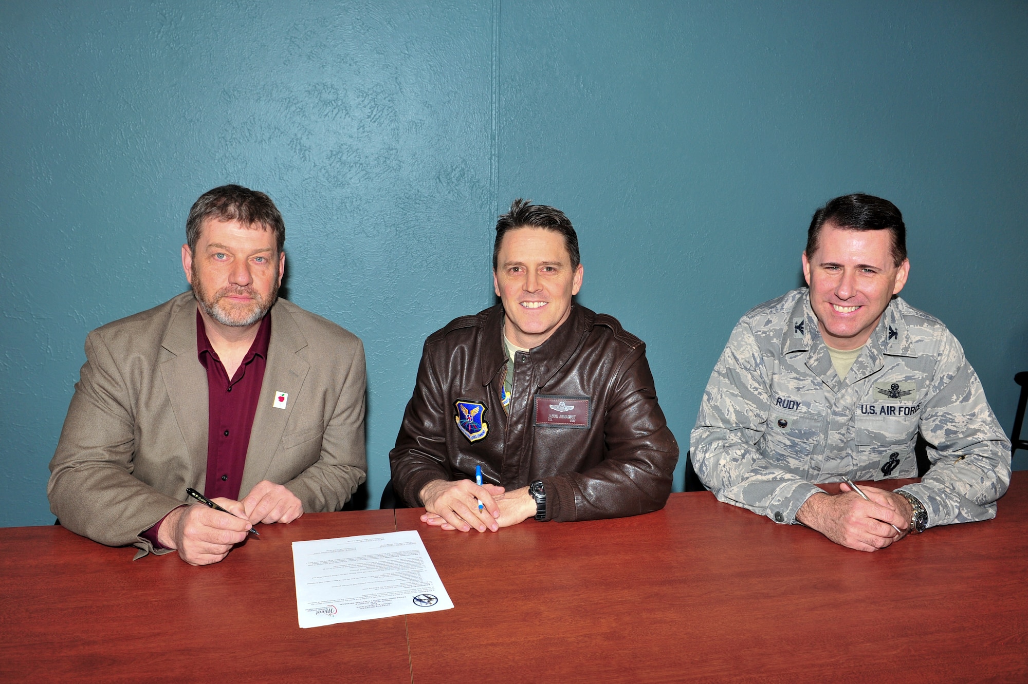 (left) Mark Vollmer, Minot Public Schools superintendent, (middle) Col. Jason Armagost, 5th Bomb Wing commander, and (right) Col. Thomas Rudy, 91st Missile Wing vice commander, prepare to sign a document for the adopt a school program in Minot , N.D., April 7, 2015. The document was a charter between the base and public schools where one of the base’s responsibilities is to provide volunteers to assist the schools with beautification, guest speakers, chaperones, etc…. (U.S. Air Force photo/Senior Airman Malia Jenkins)  