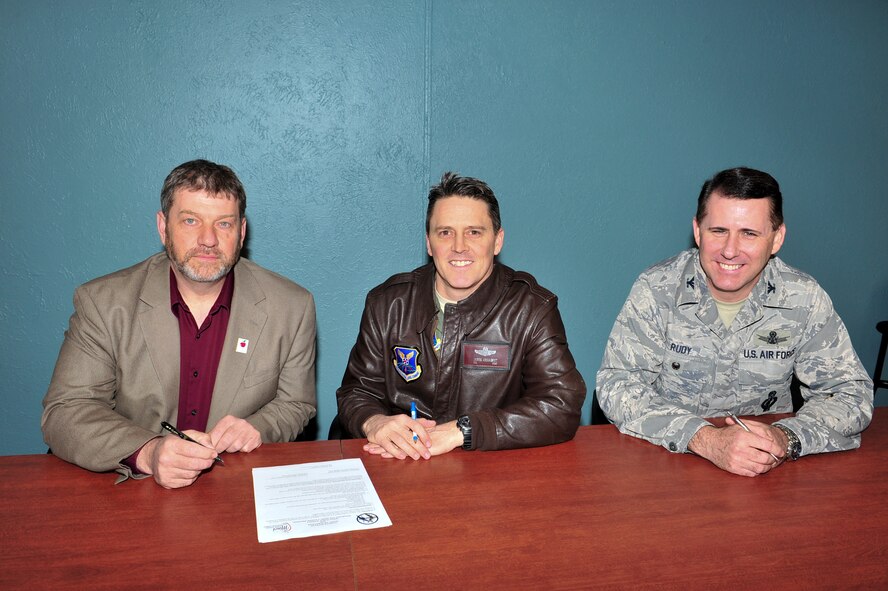 (left) Mark Vollmer, Minot Public Schools superintendent, (middle) Col. Jason Armagost, 5th Bomb Wing commander, and (right) Col. Thomas Rudy, 91st Missile Wing vice commander, prepare to sign a document for the adopt a school program in Minot , N.D., April 7, 2015. The document was a charter between the base and public schools where one of the base’s responsibilities is to provide volunteers to assist the schools with beautification, guest speakers, chaperones, etc…. (U.S. Air Force photo/Senior Airman Malia Jenkins)  