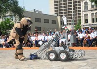 Senior Airman Corey Mcenery, 502nd Civil Engineer Squadron Explosive Ordnance Disposal technician at Joint Base San Antonio-Lackland, demonstrates the uses of a bomb suit and robot as part of bomb disposal procedures during Air Force at the Alamo events in conjunction with Fiesta San Antonio April 20.  The suit weighs about 80 pounds and protects Airmen from explosives at an arm’s length, or roughly three feet.  The robot is used to keep Airmen safe at a greater distance and can be used to inspect and remove a suspicious package.  (U.S. Air Force photo by Melissa Peterson/released)