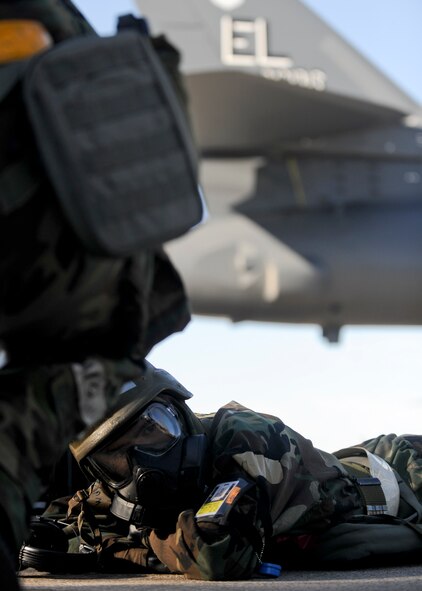Airman 1st Class Clay Steiber, 28th Aircraft Maintenance Squadron crew chief, takes cover during an operation readiness exercise at Ellsworth Air Force Base, S.D., March 31, 2015. The training exercise evaluated a variety of the installation’s units that help support the operational mission at Ellsworth, including aircraft maintenance, base defense, damage assessment, Chemical, Biological, Radiological, Nuclear, and High Yield Explosives (CBRNE) reconnaissance.  (U.S. Air Force photo by Senior Airman Anania Tekurio/Released)