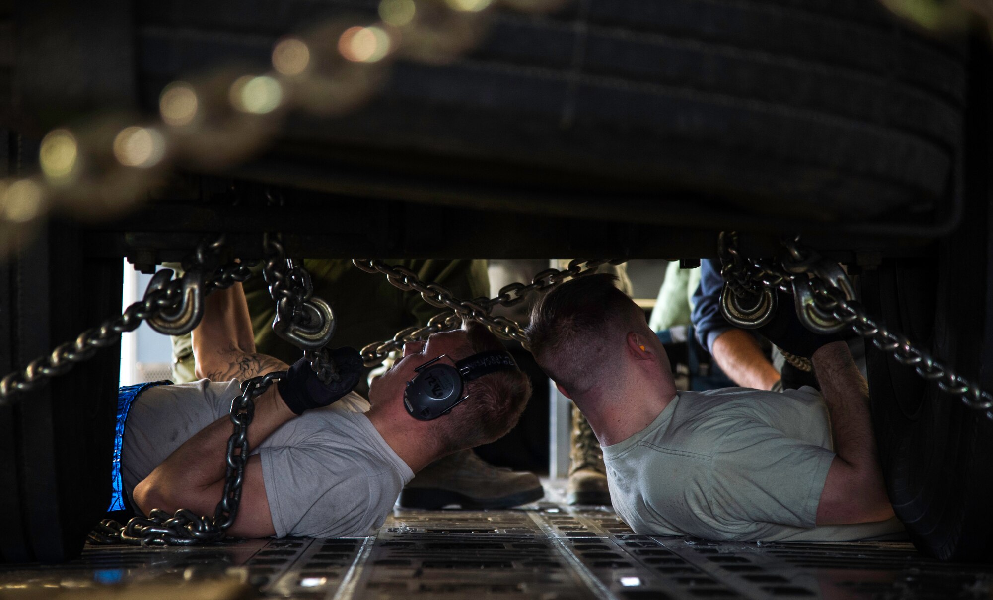 Staff Sgt. Preston Harris and Staff Sgt. Travis Thomas, 89th Aerial Port Squadron aircraft specialists, chain down a generator to the floor of a C-17 Globemaster III at Joint Base Andrews, Md., April 15, 2015. Aircraft specialists crisscross chains with hooks to secure cargo and ensure flight safety. (U.S. Air Force photo/Airman 1st Class Philip Bryant)