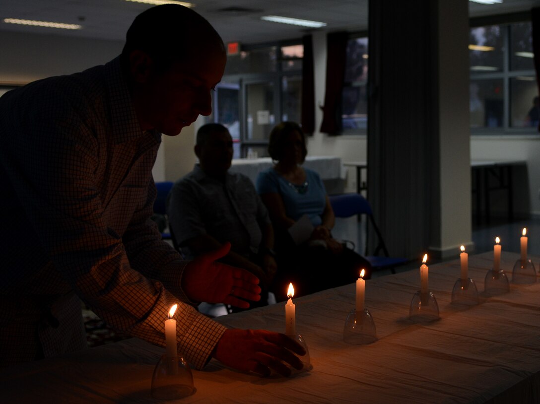 Tech. Sgt. Alexander Puma, 39th Air Base Wing Legal Office NCO in charge of military justice, places a candle after lighting it during a Holocaust Remembrance Ceremony April 17, 2015, at Incirlik Air Base, Turkey. The ceremony was held to recognize the National Days of Remembrance, which honors those who suffered and perished during the Holocaust. (U.S. Air Force photo by Staff Sgt. Caleb Pierce/Released) 