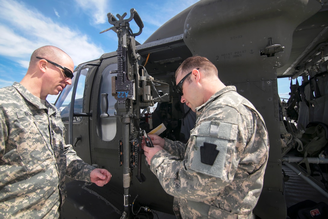 Army crew chiefs prepare M240B machine guns for UH-60 Black Hawk helicopters on the flightline before participating in aerial gunnery training at the Army Aviation Support Facility, on Joint Base McGuire-Dix-Lakehurst, N.J., April 16, 2015.