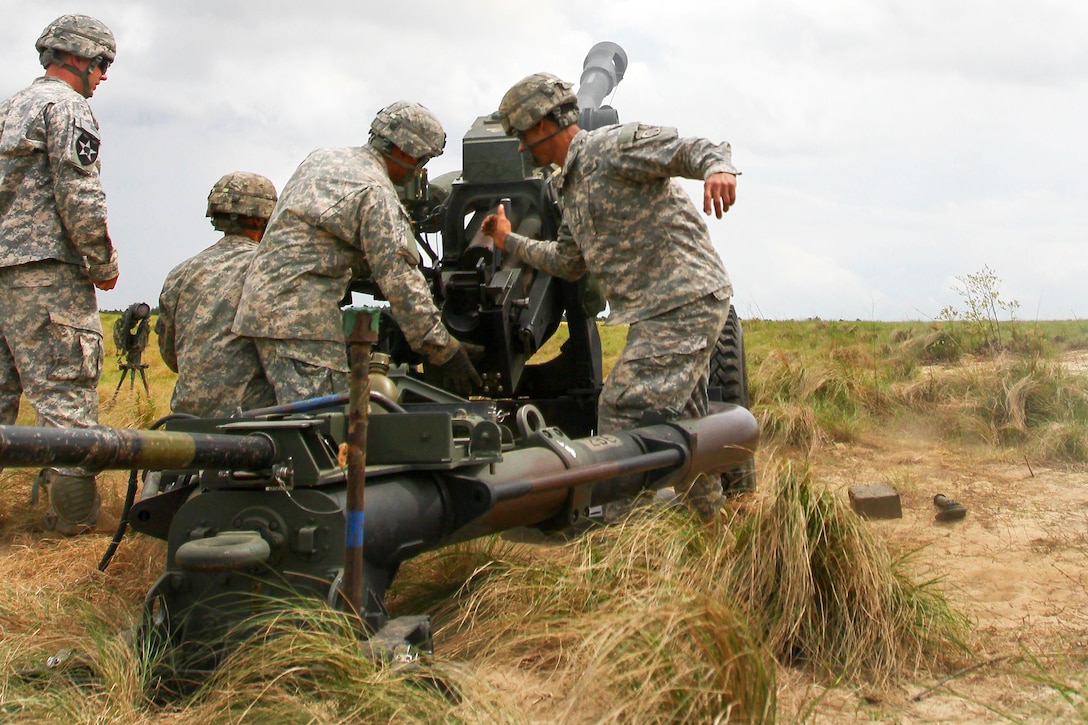 Army paratroopers eject a casing after firing a round from an M119A3 ...