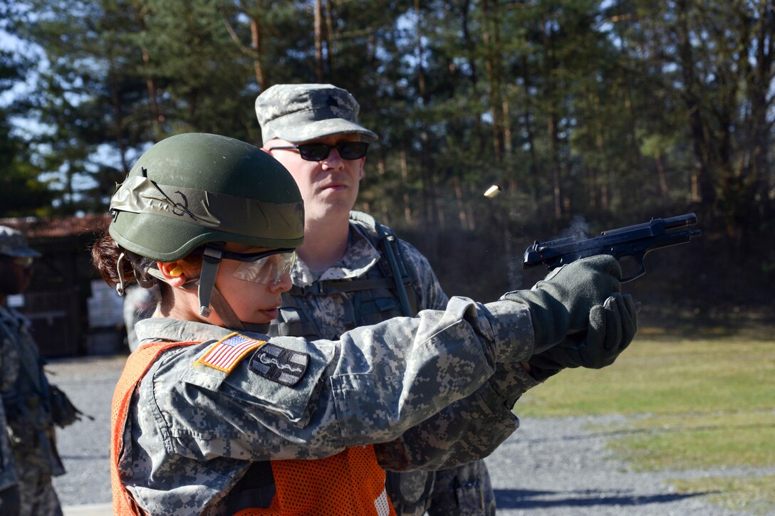 U.S. Army Spc. Elizabeth Martinez, foreground, fires an M9 pistol during the Best Warrior Competition on Grafenwoehr Training Area, Germany,  April 15, 2015. Martinez is assigned to U.S. Army Landstuhl Regional Medical Center, Europe Regional Medical Command.