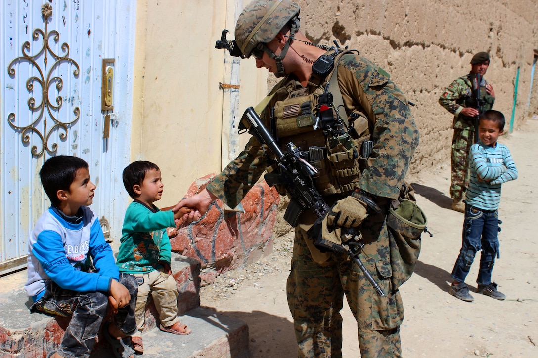 A U.S. Marine shakes hands with an Afghan child while on patrol near ...