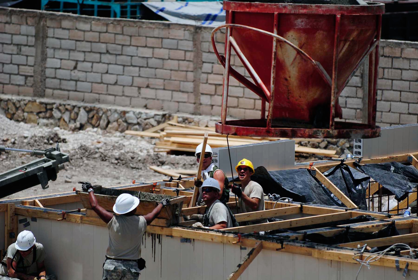 Soldiers of the Louisiana National Guard’s 205th Engineer Battalion, 225th Engineer Brigade, pour concrete to secure the wall for the U.S. Army South New Horizons- Haiti 2010 Diaquoi project site in Gonaives, Haiti, July 14, 2010.
